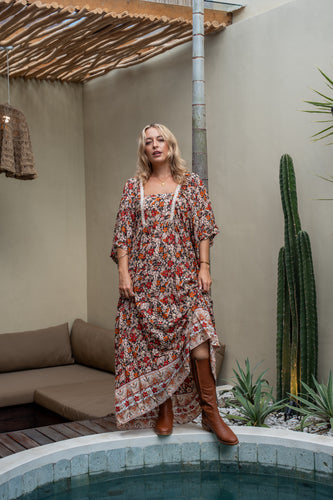 A woman wearing bohemian floral maxi dress standing beside the pool area. 